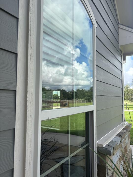 Arched window on gray siding after cleaning