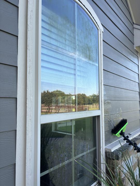 Arched window on gray siding before cleaning