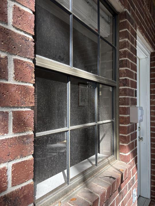 Divided-pane window on brick wall before cleaning
